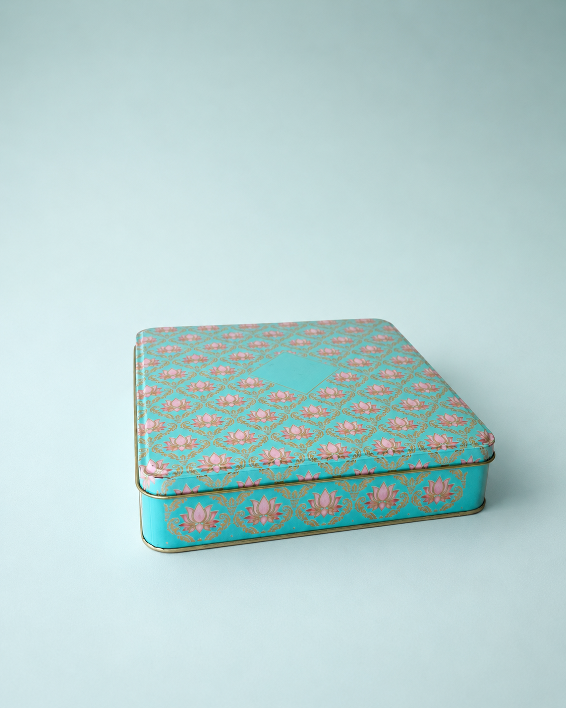 A teal printed tin hamper box with an intricate floral pattern, green base, and fitted lid, suitable for sweets, chocolates, dry fruits, beauty products, and keepsakes.