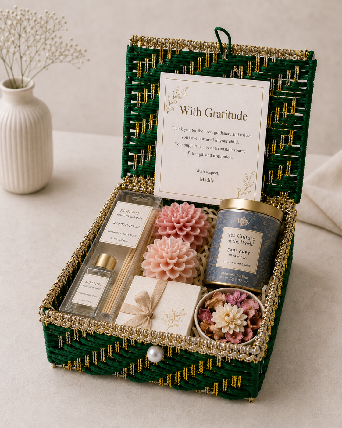 Warm Wishes Trunk featuring a reed diffuser, two floral-scented candles, tea tin, chocolate gift box, potpourri bowl, personalized gratitude card, flowers, and fillers in a green wedding trunk.