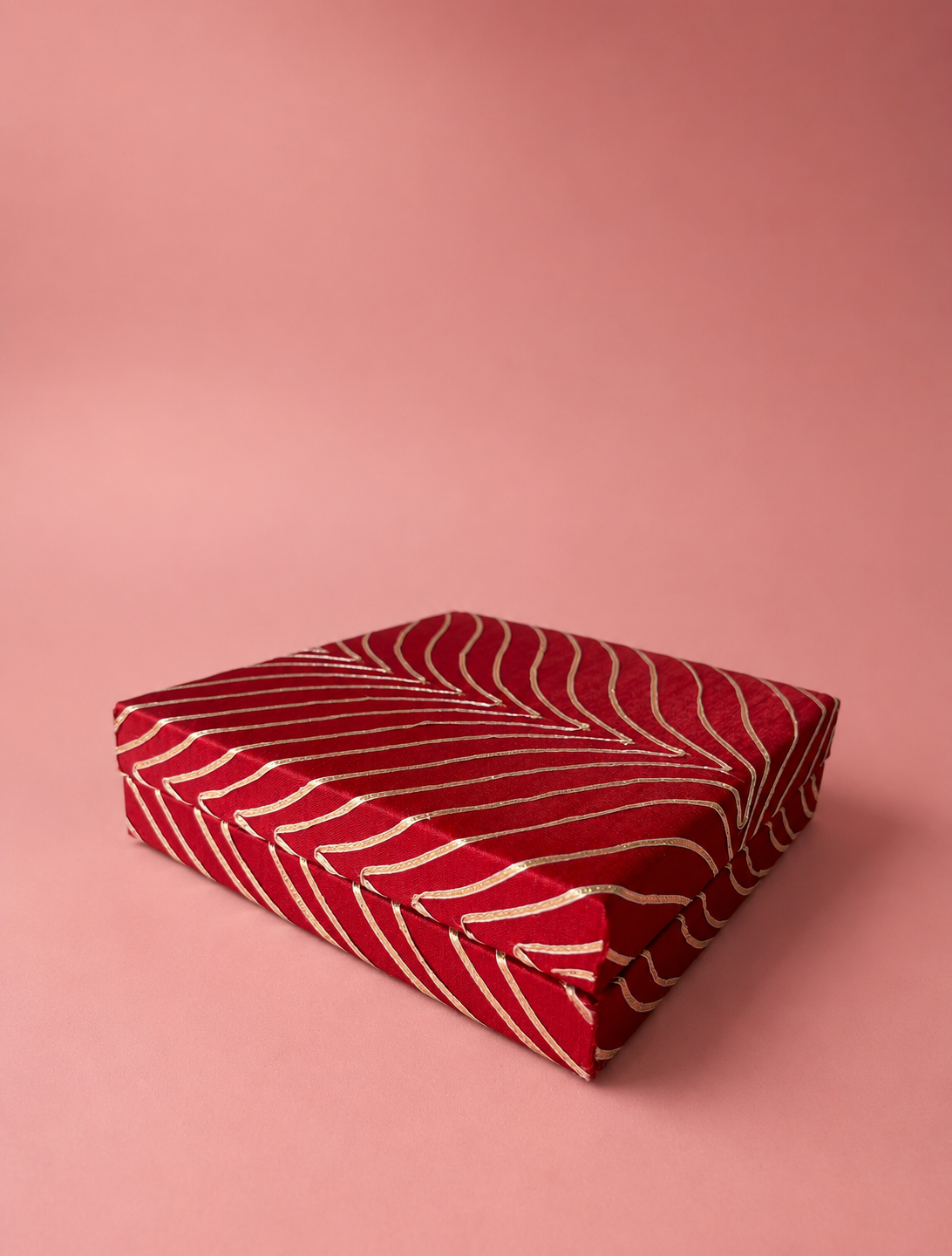 A red and gold half-kilogram mithai box with a flowing wave pattern, designed for presenting traditional sweets and confectionery during Diwali, weddings, and festive celebrations.