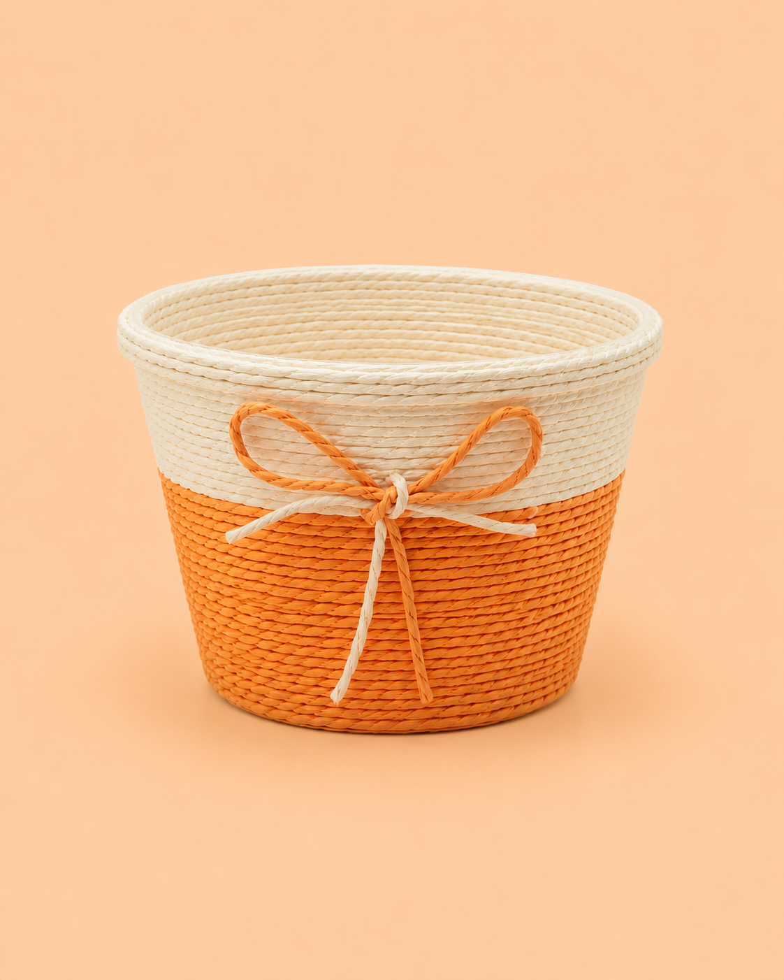 A small orange and beige woven gift basket with a decorative jute bow, ideal for chocolates, flowers, dry fruits, return gifts, and festive hamper presentations.