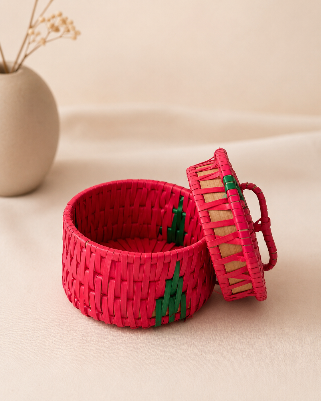 A handcrafted round red palm leaf gift box with a matching woven lid and handle, suitable for festive gifting, sweets, dry fruits, chocolates, and keepsakes.
