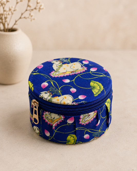 A round blue floral printed fabric dabbi with a zip closure, designed for gifting jewellery, chocolates, dry fruits, and small keepsakes during festive occasions.