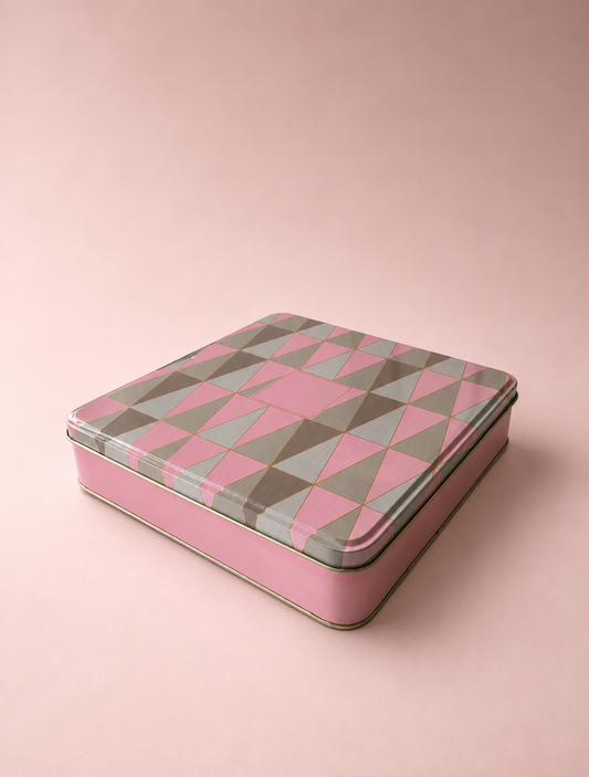 A pink printed tin hamper box with a geometric blush and rose pattern, metallic interior, and fitted lid, suitable for chocolates, sweets, dry fruits, beauty gifts, and keepsakes.