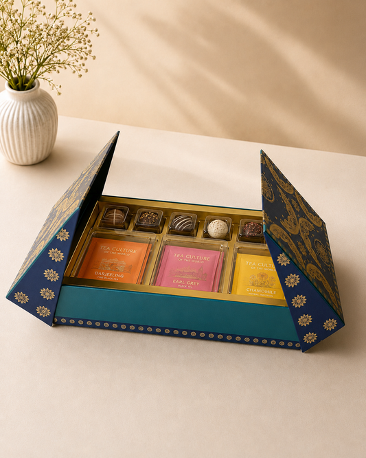 A blue designer gift box with assorted tea sachets, premium chocolates, truffles, and a compartmentalized sweet box, elegantly arranged for festive and corporate gifting.