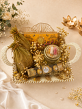 A festive white woven basket Rakhi hamper featuring Ferrero Rocher chocolates, a decorative jar, roli chawal set, festive gift box, potli, and elegant floral styling for Raksha Bandhan gifting.
