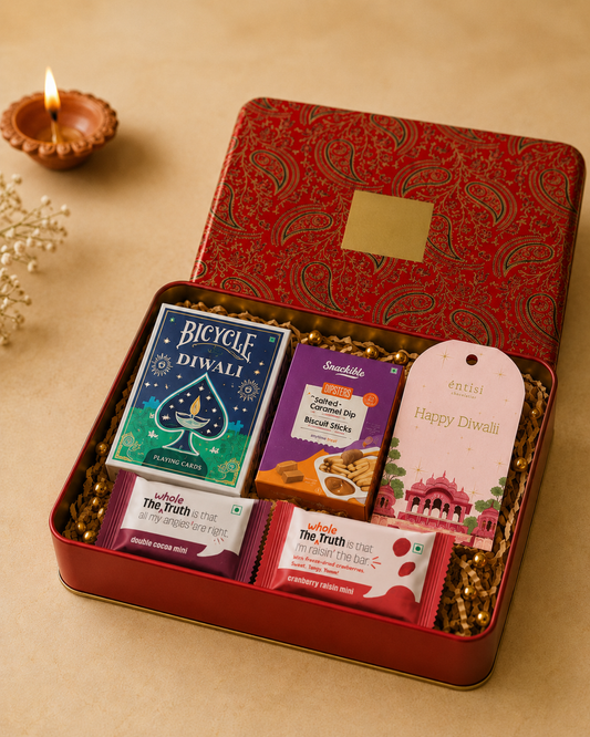 The Shuffle & Serve Hamper in a red printed hamper box with Bicycle Diwali playing cards, caramel dipsters, biscuit sticks, protein bars, and a Diwali greeting card.