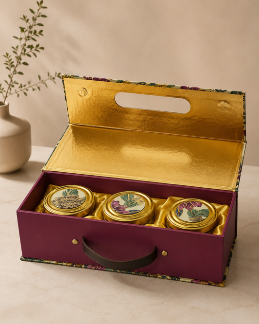 A floral designer gift box with a carry handle, featuring three premium jars and a gold-finished interior, ideal for customized festive and corporate gifting.