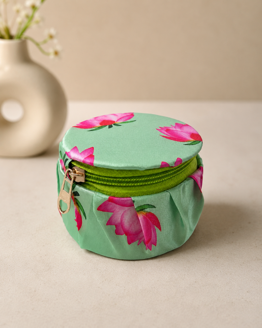 A small round green floral printed fabric dabbi with a zip closure, ideal for gifting jewellery, chocolates, dry fruits, and festive keepsakes.